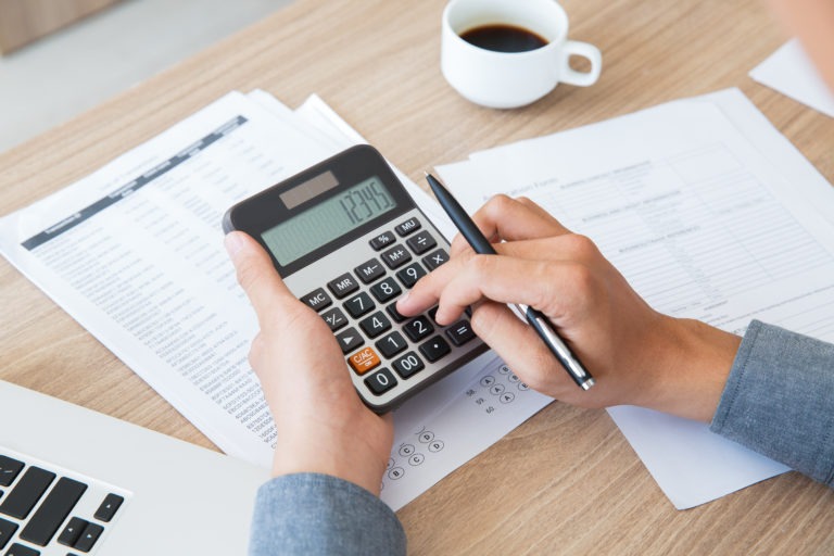 man using calculator to count income and outcome lecture de son bilan et son compte de résultat