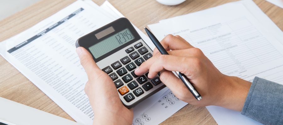 man using calculator to count income and outcome lecture de son bilan et son compte de résultat