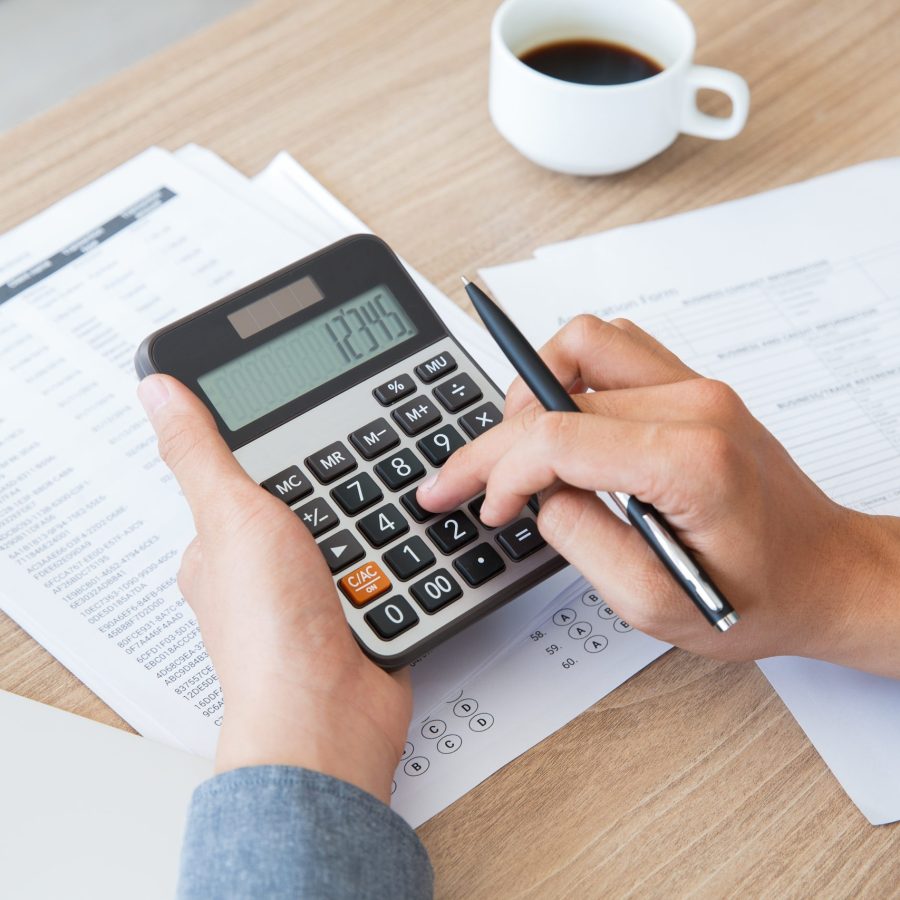 man using calculator to count income and outcome lecture de son bilan et son compte de résultat