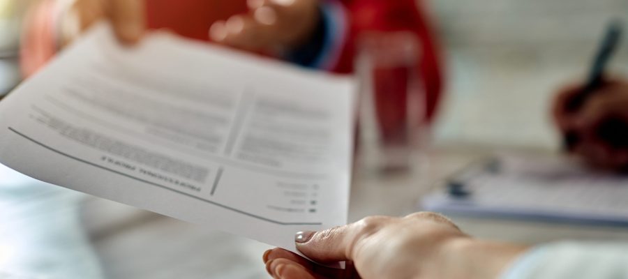 close up of a candidate giving his cv while applying for a job.