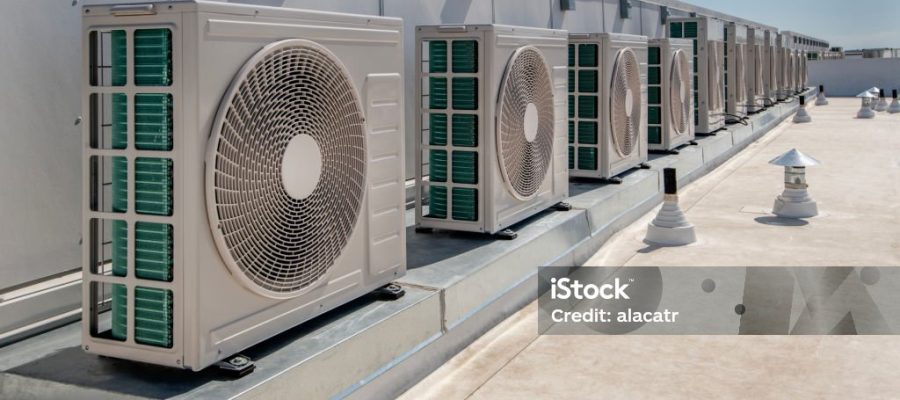 long row of air conditioner units on a membrane roof.
