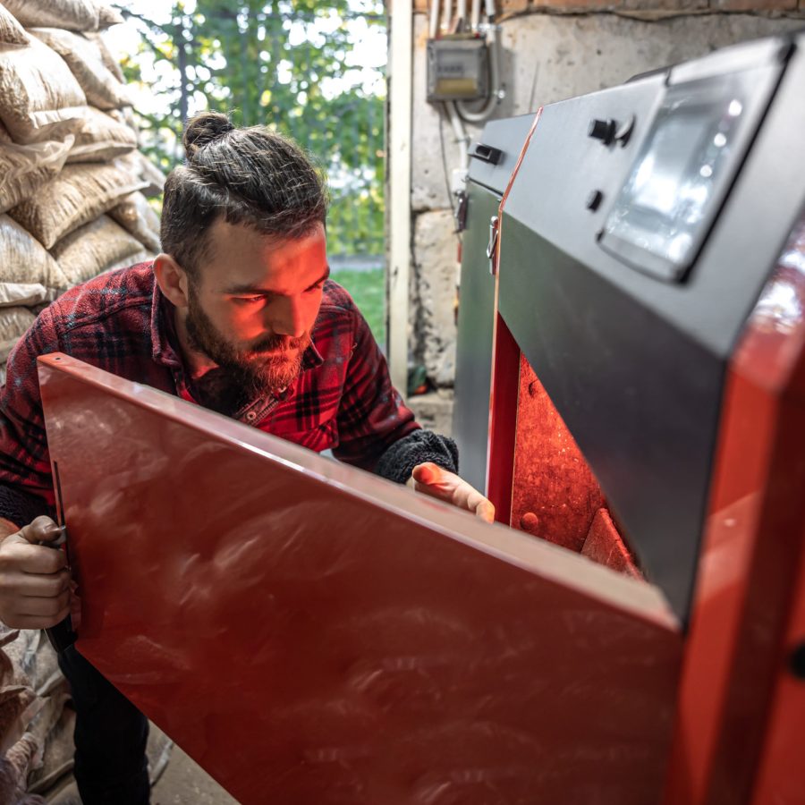 a man looking into a boiler on solid fuel, open door boiler with flames of fire.